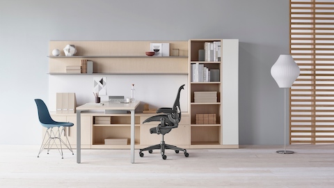 Canvas Private Office com armário em madeira clara, prateleiras no alto, cadeira de escritório Aeron preta e cadeira azul em plástico moldado Eames.