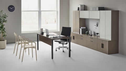 Canvas Private Office com armário em vidro e madeira, cadeira de escritório Eames Aluminum Group preta e duas cadeiras de escritório Branca em madeira clara.
