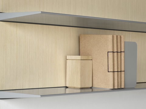 Una imagen en primer plano de los estantes flotantes de aluminio sobre un panel trasero de madera clara.