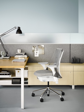 A Canvas Storage workstation in light wood with a grey screen and a white Sayl office chair.