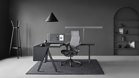 Una estación de trabajo Canvas Vista en negro y gris con una silla para oficinas Cosm gris oscuro.