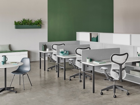 Una estación de trabajo Canvas Wall con pantallas grises, almacenamiento superior y sillas para oficina Mirra 2 blancas.