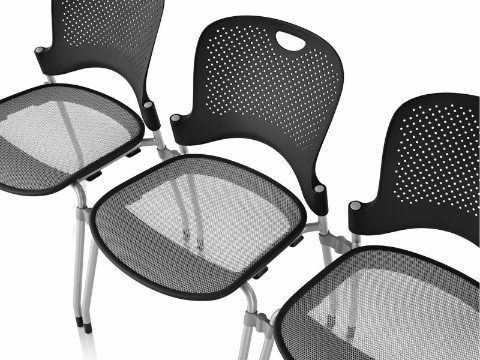 Vue aérienne de trois chaises empilables noires Caper avec le siège FLEXNET en option.