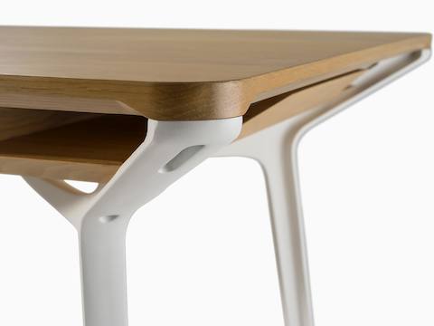 白い脚とCarafeテーブルの明るいウッドグレインの上端との間の接続のクローズアップ。厳格なフィット感と仕上がりを示します。