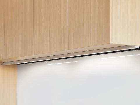 An illuminated Cast LED Light with valance installed underneath a light wood upper cabinet. An illuminated Cast LED Light with valance installed underneath a light wood upper cabinet.