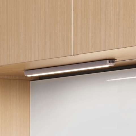 An illuminated Cast LED Light without valance installed underneath a light wood upper cabinet. An illuminated Cast LED Light without valance installed underneath a light wood upper cabinet.