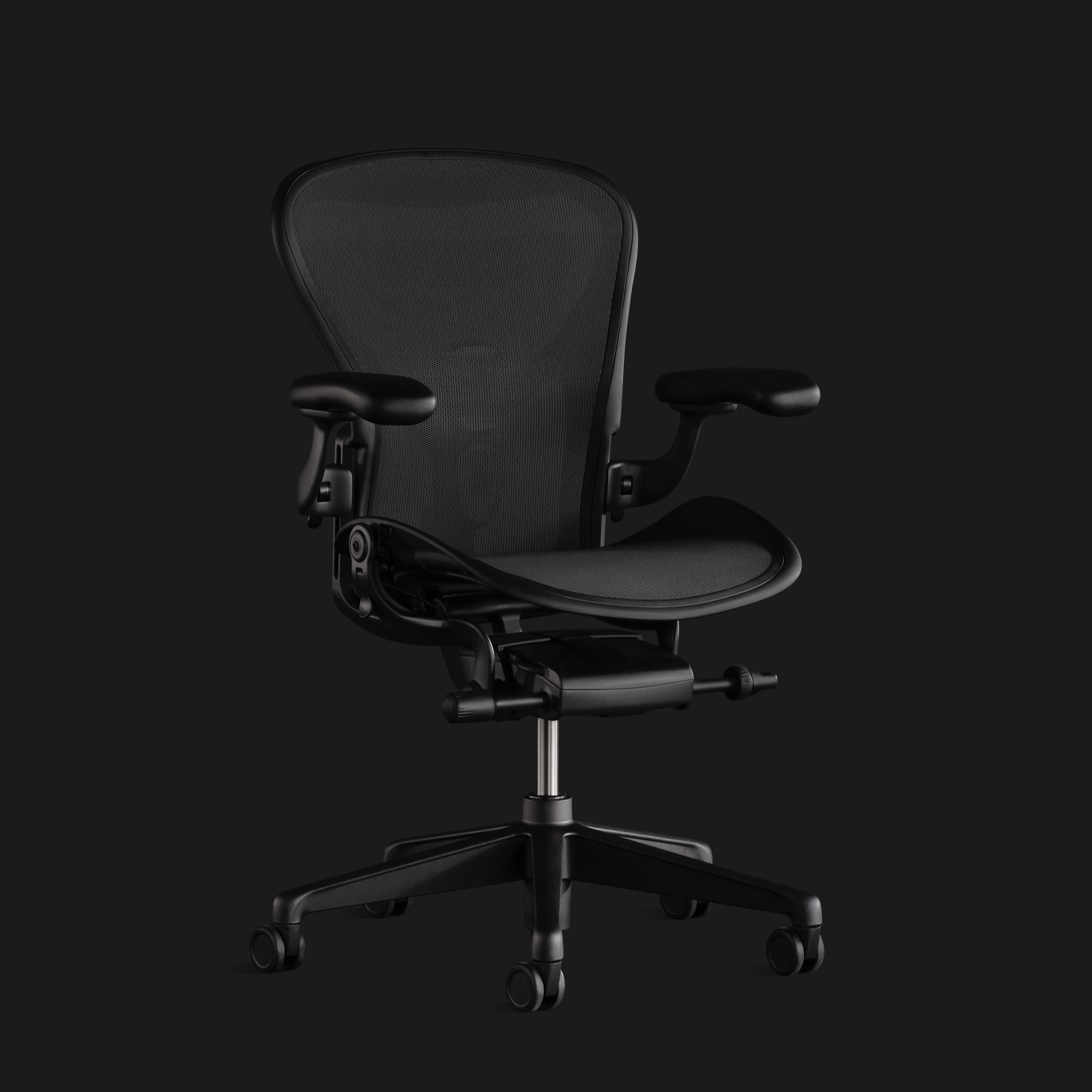 Ein Aeron Stuhl ganz in Schwarz vor einem schwarzen Hintergrund, leicht schräg von vorne betrachtet.