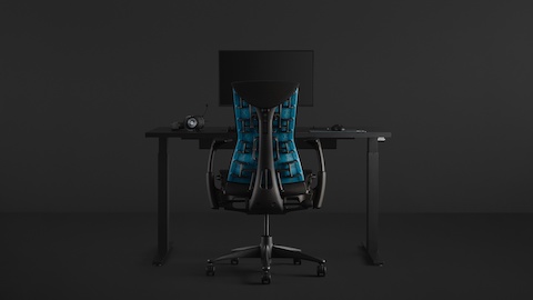 모두 검은색 배경에서 Motia Gaming Desk와 그 위에 Ollin Monitor Arm을 설치하고 Embody Gaming Chair를 배치한 풀 게이밍 환경.