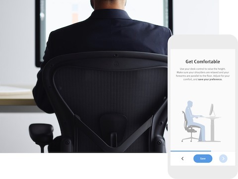 A back-view photo of a person sitting in an Aeron Chair and facing a monitor. The photo is overlaid with a image of the wellness app. 