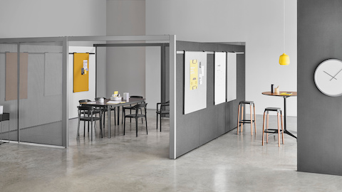 A semi-enclosed Overlay room with two entryways, gray perforated metal exteriors, and markerboard interiors with a table and six chairs inside.