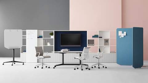 A Locale sit-to-stand workstation with a blue Mirra 2 office chair near a collaborative meeting setting with grey fabric upholstered Setu chairs.