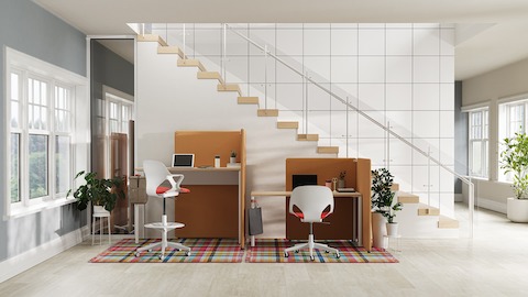 Eine helle Büroumgebung aus hellbraunen freistehenden Trennwänden um OE1 Tische mit weißen und roten Zeph Stühlen.