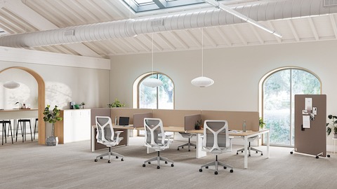 Eine helle Büroumgebung aus Layout Studio Arbeitsplätzen mit braunen Trennwänden, Cosm Stühlen sowie einer braunen mobilen Trennwand im Hintergrund.