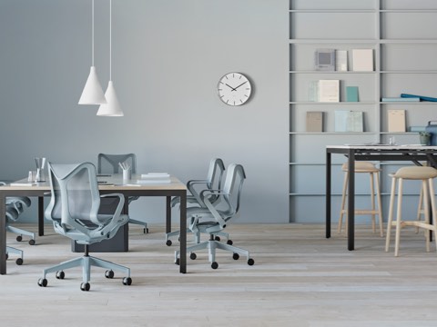 Cadeiras Cosm azul claro e banquetas marrom claro ao redor de mesas Layout Studio.