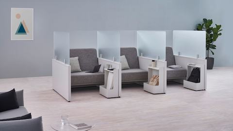 利用玻璃屏风和Ubi Mobile Bag Catch（Ubi移动型包袋挂钩）配件封闭的三个软垫座椅空间中的Catena Office Landscape组件。