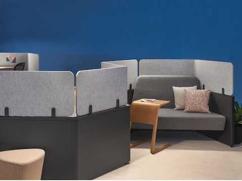 A close-up of S-Shaped Catena Office Landscape workstations integrated with gray soft seating and gray screens.