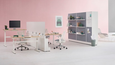 Catena Office Landscape workstations with white legs, light wood surfaced, and glass add-on screens accompanied by Sayl Chairs. Port Storage System is featured in the background.