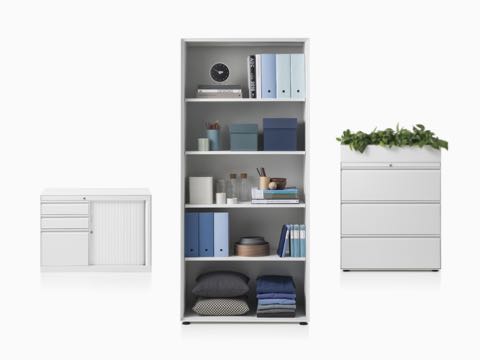 A CK8 right-hand return cabinet with shutter door compartment, CK8 open shelf high cabinet fill in with full storage item, and CK8 three-high lateral filing mid-height cabinet with planter on top. A CK8 right-hand return cabinet with shutter door compartment, CK8 open shelf high cabinet fill in with full storage item, and CK8 three-high lateral filing mid-height cabinet with planter on top.
