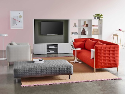 Uma área de trabalho casual com um sofá vermelho ColourForm e uma poltrona ColourForm cinza claro e otomano. Uma área de trabalho casual com um sofá vermelho ColourForm e uma poltrona ColourForm cinza claro e otomano.