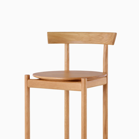 An oak bar-height Comma Stool, viewed from the front at an angle.