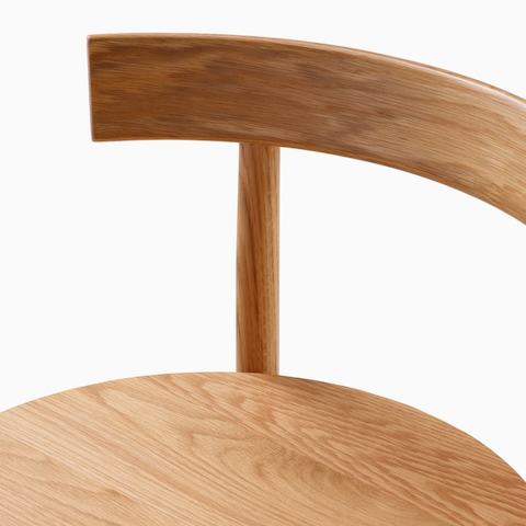 A close up detail shot of the wood seat and backrest of a Comma Stool.