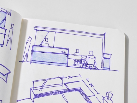 An open sketchbook with a drawing of Commend Nurses Station and two caregivers helping two patients.