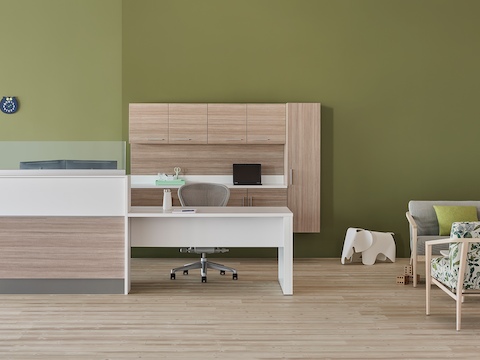 A prefab Commend Nurses Station with glass screens serving as a reception desk in an outpatient space including Palisade chairs, sofa, and table.