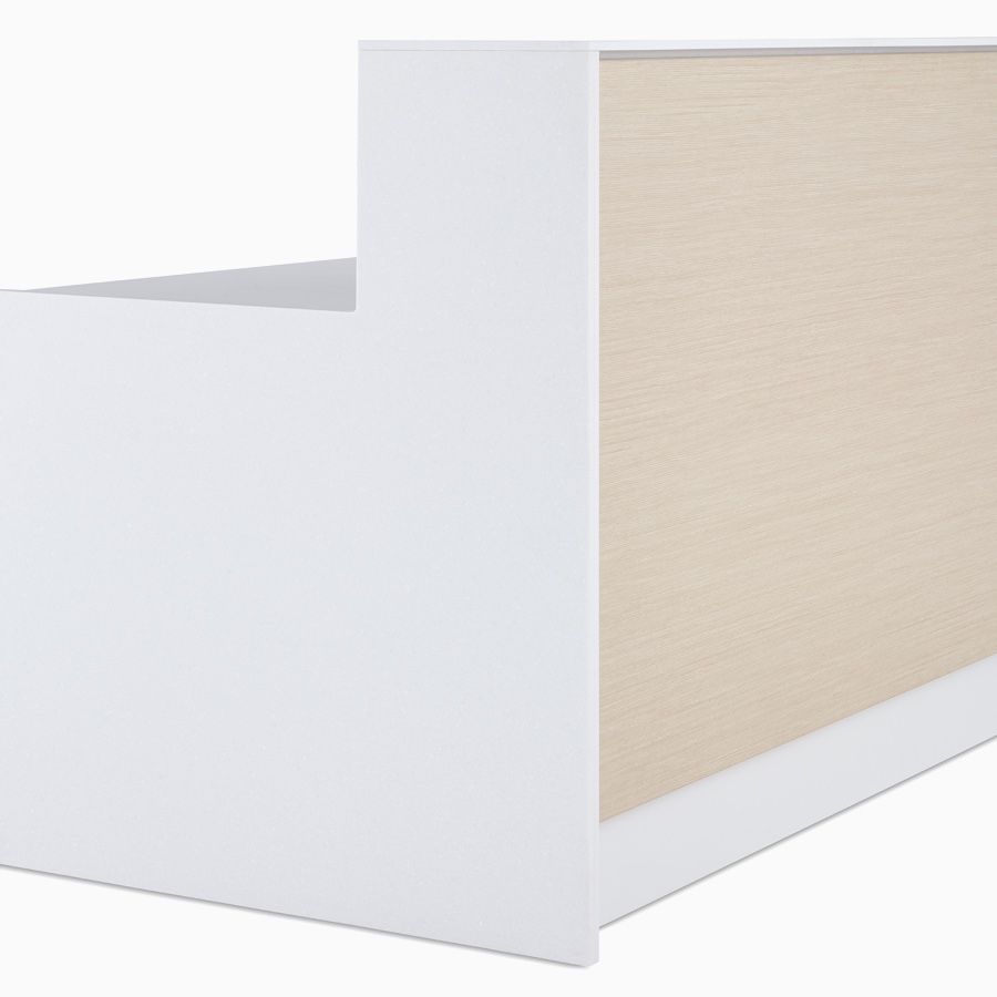 Primer plano del frente laminado exterior de que imita la madera de fresno, de una pieza, paneles finales de Corian blanco y tapas de laminado blanco en un mostrador de enfermería Commend prefabricado.