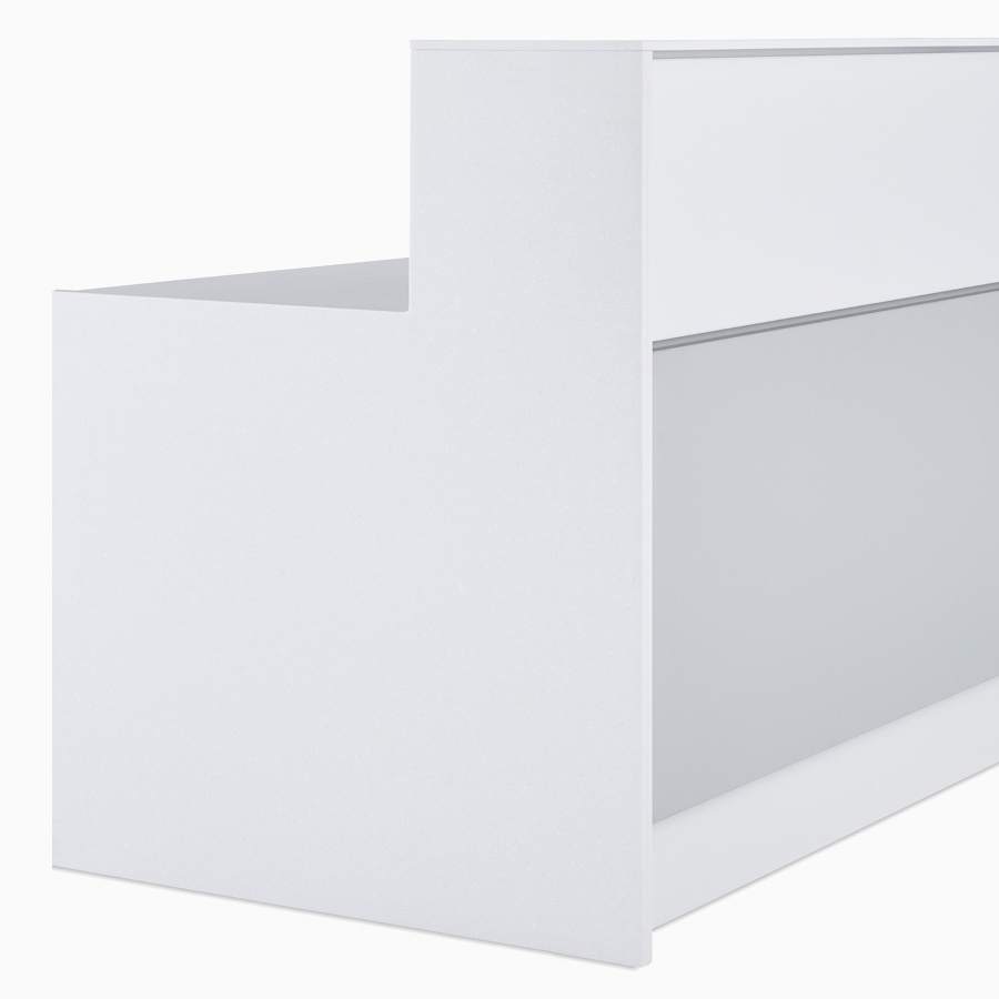 Primer plano de revestimiento exterior de dos piezas en gris y blanco, tapas de laminado blanco y paneles finales en Corian blanco en un mostrador de enfermería Commend prefabricado.