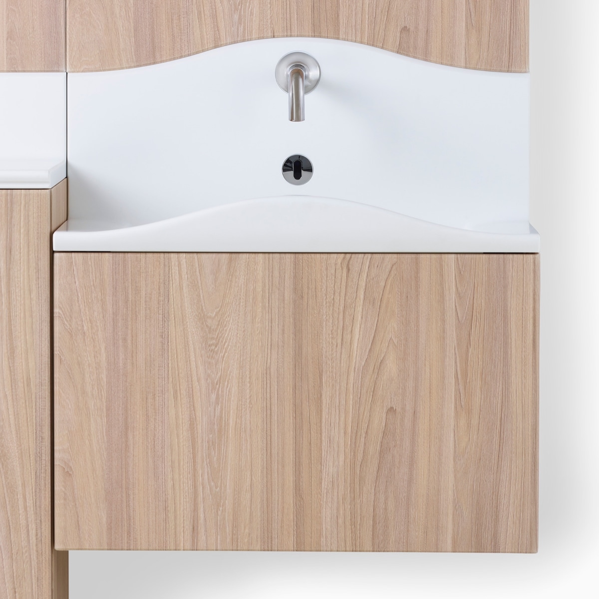 A close-up view of white Corian sink in Compass System in a medium wood finish.