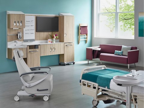 A patient room with a bed, recliner, guest sofa, and Compass System modular components.