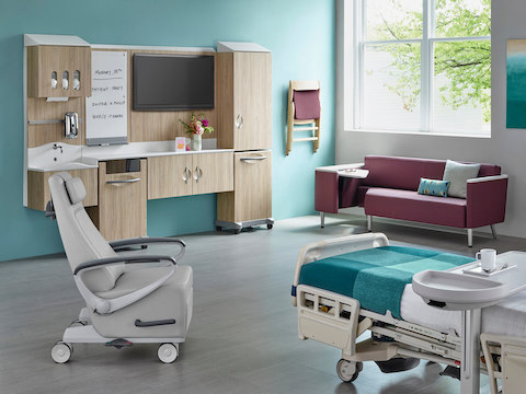 A patient room with a bed, recliner, guest sofa, and Compass System modular components.