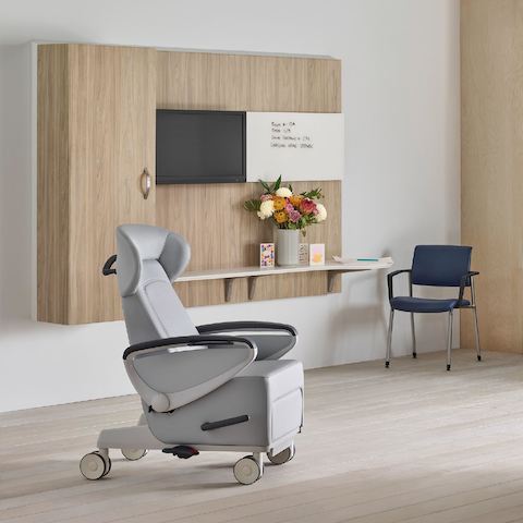 Compass System casework footwall in a medium elm wood finish with a blue Ava patient chair and a Verus side chair in blue.