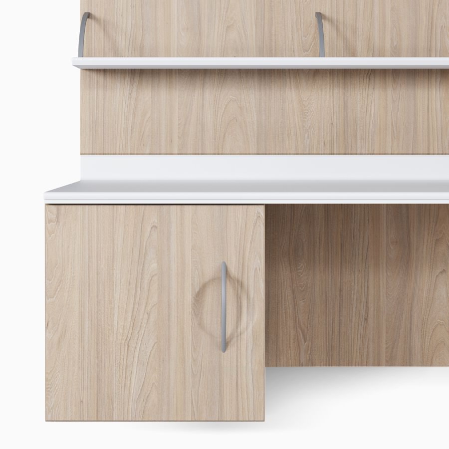 Compass casework storage unit with a door mounted in an elm wood finish, under a white solid surface work surface attached to wall tiles.