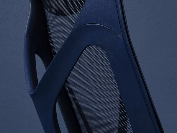 A Nightfall dark blue Cosm Chair features an illustration highlighting the chair's flexible frame. 