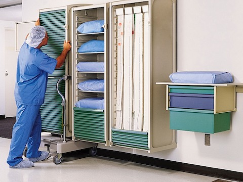 A healthcare worker positions a movable Co/Struc locker on a wall rail. 