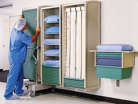 A healthcare worker positions a movable Co/Struc locker on a wall rail. 