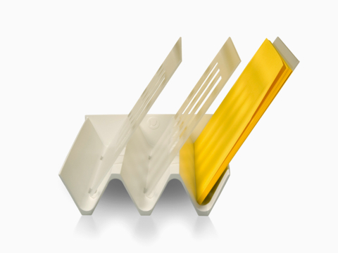 Una bandeja diagonal de color masilla con tres ranuras, una de las cuales tiene papel amarillo.