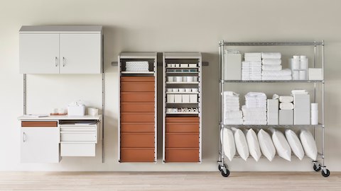 Medical clean utility supply room in soft white Co/Struc System, procedure and supply lockers with terra cotta drawers, and a stainless steel wire shelving unit.