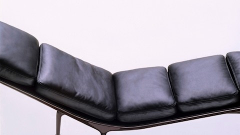 An overhead profile view of a black leather Eames Chaise with an eggplant frame. 