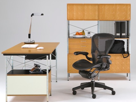 Una estación de trabajo creada combinando una silla de oficina Aeron negra con una unidad de almacenamiento y escritorio Eames, ambas con acentos neutros.