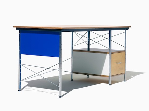 Uma vista em ângulo de um Eames Desk com detalhes de bétula, branco e azul, enfatizando os suportes cruzados de aço.