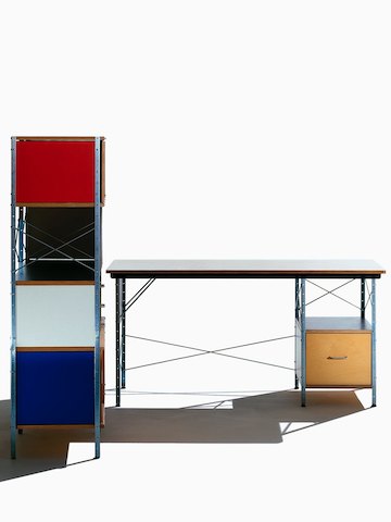 Vista frontal de una mesa Eames en colores neutros junto a una unidad de almacenamiento Eames con acentos brillantes, que se muestra de costado. Vista frontal de una mesa Eames en colores neutros junto a una unidad de almacenamiento Eames con acentos brillantes, que se muestra de costado.
