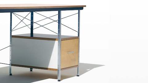 Una vista en ángulo de un escritorio Eames con acentos de abedul, blanco y azul, haciendo hincapié en los soportes cruzados de acero.