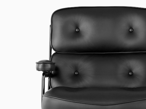 Vista cercana del detalle del botón en el lujoso cojín trasero de una silla ejecutiva de cuero negro Eames.