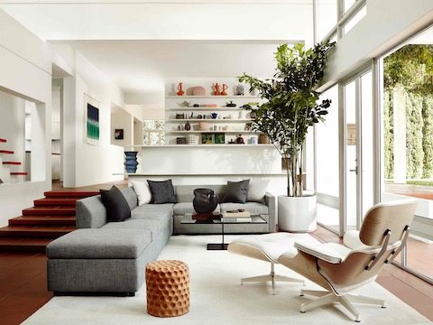 Three-quarter rear view of a white leather Eames Lounge Chair and Ottoman in a residential setting. 