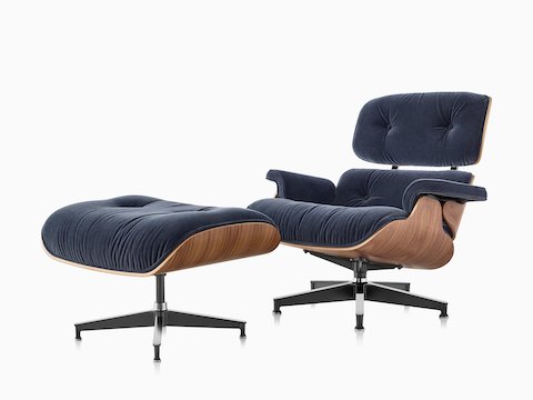 Eames Lounge Chair e Otomano com estofamento de mohair azul e um revestimento de madeira, visto de um ângulo de 45 graus.