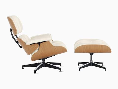 Vista de perfil de una silla lounge y un descansa pies Eames con chapa de madera de roble en blanco.