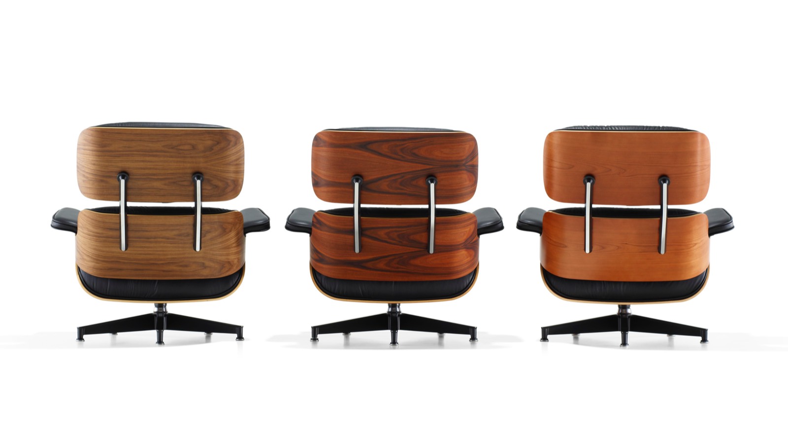 Três Eames Lounge Chairs, cada um com um acabamento de madeira diferente, visto de trás.