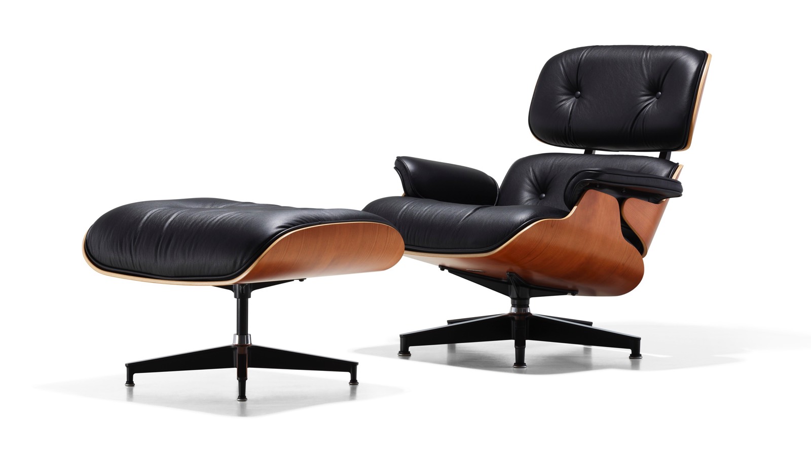 Couro preto Eames Lounge Chair e Otomano com um revestimento de madeira, visto de um ângulo de 45 graus.